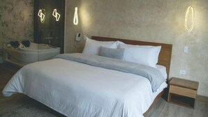 A modern hotel room with a large bed, a built-in bathtub, and a mirror. - Saya Hotel & Suites (Sayausi)