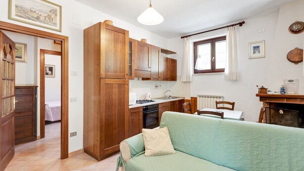 A compact living space with a kitchenette, a dining area, and a sofa. - Majestic Villa Retreat (Assisi)