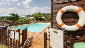 A pool area with wooden deck, lounge chairs, and umbrellas. - Majestic Villa Retreat (Assisi)