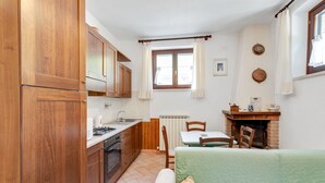 A compact kitchen with wooden cabinets, a stove, and a dining area with a table and chairs. - Majestic Villa Retreat (Assisi)