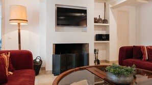 Ein Wohnzimmer mit Kamin, einem Flachbildfernseher und zwei roten Sofas.
