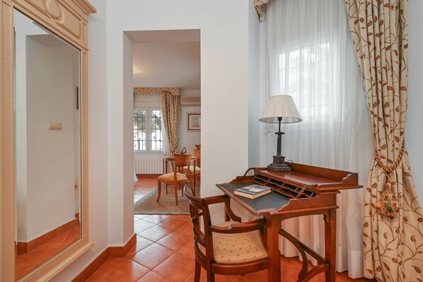 A room with a wooden desk, a lamp, a chair, and a view of a dining area. - Villa Serenita - Moraira, Costa Blanca (Moraira)