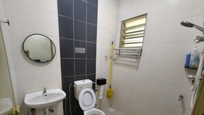 Casa de banho com sanita, lavatório, espelho e janela.
