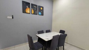Uma sala de jantar com uma mesa de mármore e seis cadeiras, parede cinzenta com três obras de arte emolduradas e um interruptor de luz.