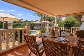 Eine Außenpatio mit Pool, Holzmöbeln und Sonnenschirmen.