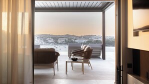 An open balcony with a view of a coastal town, wicker furniture, and a table. - Infinity Rise Villa, a Distinctive Private Stay (Agia Pelagia)