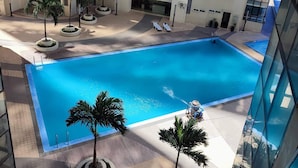 Una piscina circondata da palme e un edificio a più piani con balconi.