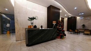 Una reception di hotel con un bancone in marmo, un albero di Natale e un orologio appeso al muro.