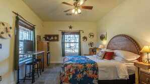 A bedroom with a bed, a desk, a chair, a ceiling fan, and a window. - Buffalo Spirit - Stardust Inn - Triple Z (Medicine Park)