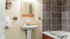 Un baño con lavamanos, espejo, ducha y bañera.
