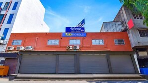 A building with a closed garage door, a sign for 'fabHOTELS,' and a flag. - HOTEL NIDHIVAN   (Surat)