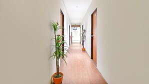 A hallway with wooden doors, potted plants, and a tiled floor. - HOTEL NIDHIVAN   (Surat)