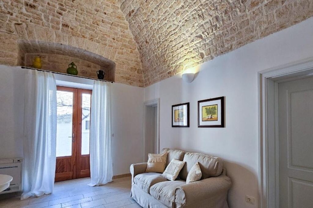 A room with a stone ceiling, a wooden door, a beige sofa, and two framed pictures on the wall.