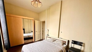 Een slaapkamer met een bed, een stoel, een spiegel en een kledingkast.