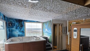 Una habitación con un jacuzzi, un ventanal grande y una puerta que da a otra zona.