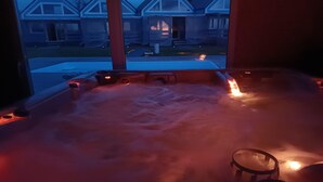 Jacuzzi con control remoto, vapor ascendente y vista a casas a través de una ventana.