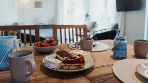 Ein Esstisch mit einer Teller Süßspeisen, einer Kaffeetasse und einer Schale Erdbeeren.