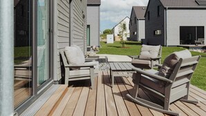 Eine Terrasse mit Gartenmöbeln, einer Glastür und Blick auf die Nachbarhäuser.