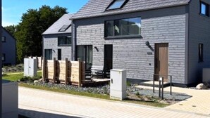 Ein modernes, zweistöckiges Haus mit geneigtem Dach, großen Fenstern und einer sichtbaren Satellitenschüssel.