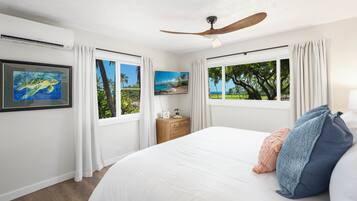 Une chambre avec un grand lit, un ventilateur de plafond, une table de chevet et un téléviseur.