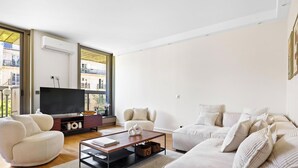 Un salon moderne avec un téléviseur à écran plat, une table basse et deux canapés.