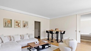 Un salon moderne comprenant un canapé, une table basse et un coin repas avec des chaises.