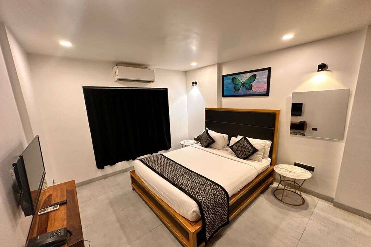 Un dormitorio con cama, mesita de noche, televisor y aire acondicionado instalado en la pared.