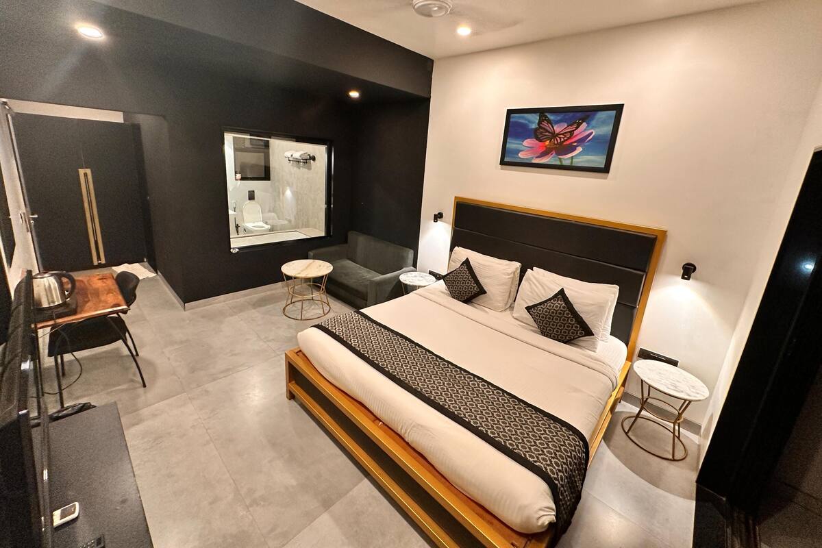 Un dormitorio moderno con una cama grande, una mesita redonda pequeña, un sofá, un espejo y un ventilador de techo.