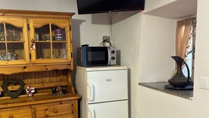 A kitchen with a wooden cabinet, a white refrigerator, a microwave, and a flat-screen TV mounted on the wall. - Pisogne, Authentic Mountain Retreat near Lake Iseo - Unique Bathroom (Pisogne)