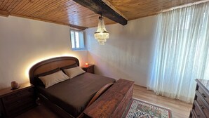A bedroom with a wooden ceiling, a bed with a headboard, a nightstand, a dresser, and a patterned rug. - Pisogne, Authentic Mountain Retreat near Lake Iseo - Unique Bathroom (Pisogne)