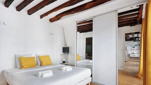 A bedroom with a bed, two yellow pillows, a TV, and a mirror. - Appartement 2 pièces à proximité du marais (Paris)