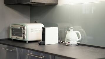 A kitchen with a toaster, a coffee maker, and a cabinet.