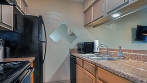 Una cocina con estufa, microondas, fregadero y armarios.