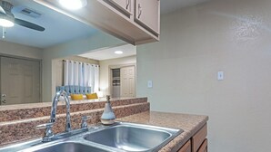 Una cocina con un lavamanos doble, encimera de granito y ventilador de techo.