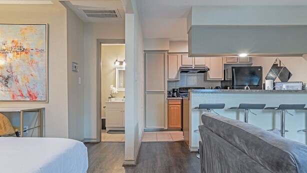 Una habitación de hotel moderna con cama, escritorio, kitchenette y baño.