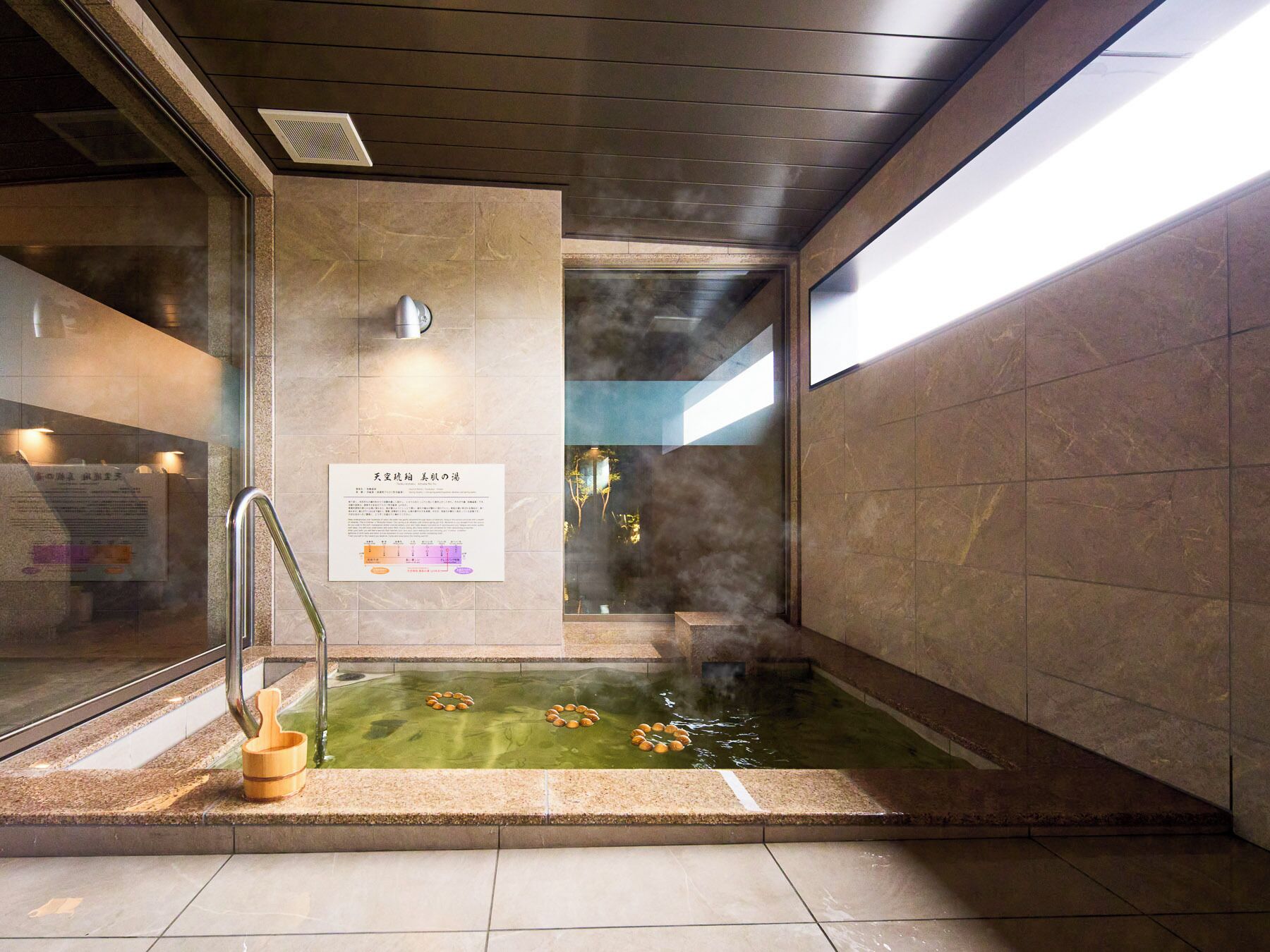 A steam room with a wooden bucket and a sign on the wall.