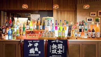 A bar area with a variety of bottles, including alcoholic beverages and sake. There are wooden cabinets and a sign with Japanese characters.