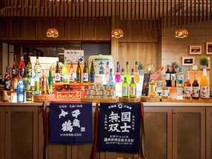 A bar area with a variety of bottles, including alcoholic beverages and sake. There are wooden cabinets and a sign with Japanese characters. - Super Hotel Premier Chitose (Chitose)
