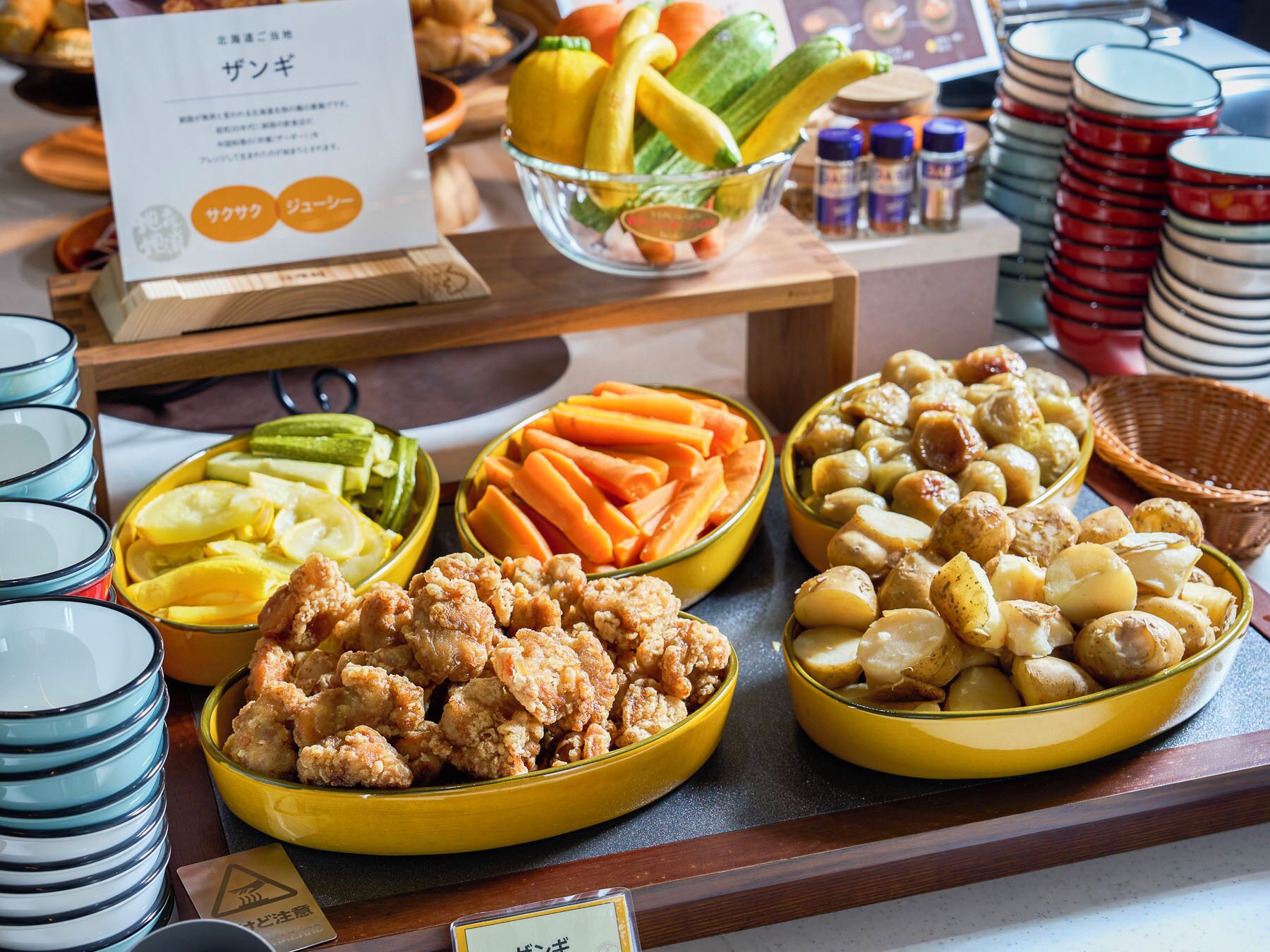 Un bufé con diversas opciones de comida, como pollo frito, papas, zanahorias y pepinillos.
