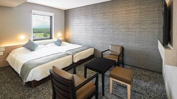 A hotel room with a bed, two chairs, a table, and a TV.