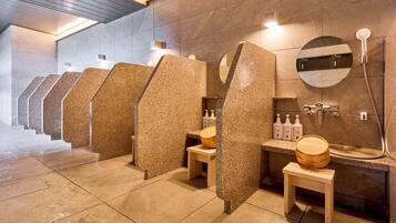 A row of private shower stalls with individual sinks and toiletries.