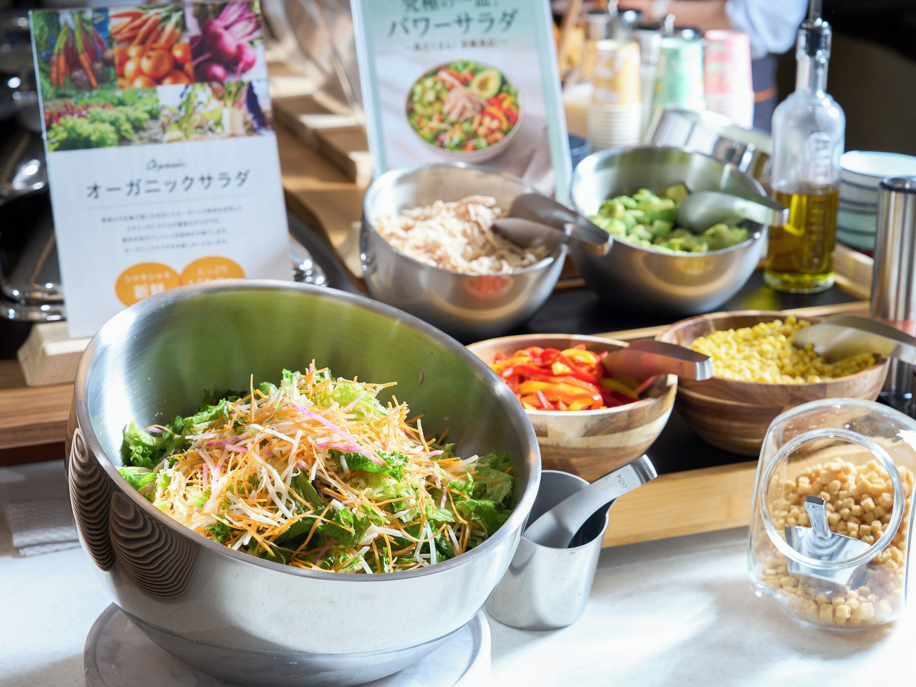 A buffet table with various dishes, including a salad with shredded cheese, bowls of vegetables, and a container of corn.