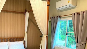 Una cama con dosel, ropa de cama blanca, cabecera de madera y una ventana con cortinas.