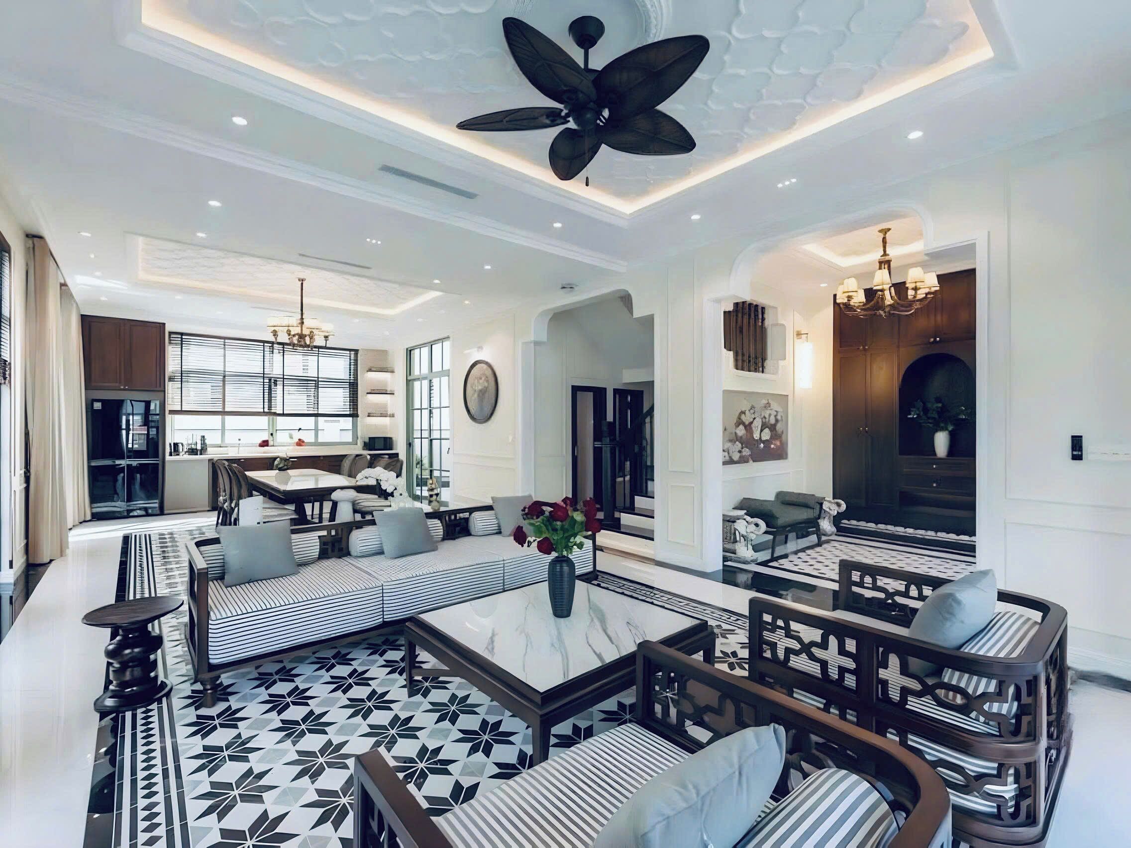 A spacious living area with a high ceiling, a central seating area with patterned cushions, and a decorative ceiling fan.