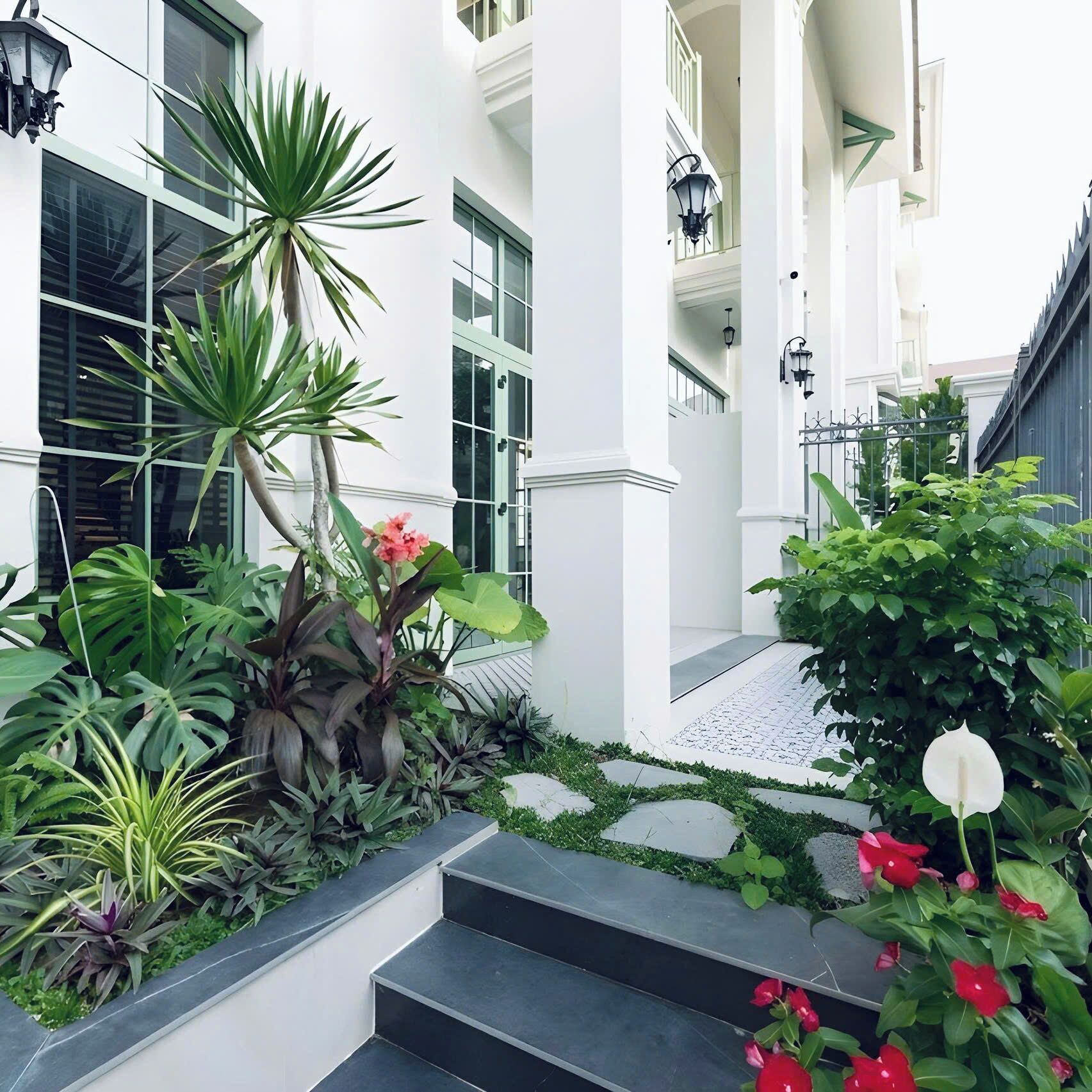 A modern building with a white facade, a staircase leading to a balcony, and various plants.