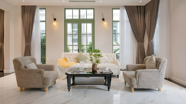 A spacious living room with a white sofa, two armchairs, a coffee table, and large windows with curtains. - Ocha Villa (Phu Quoc)