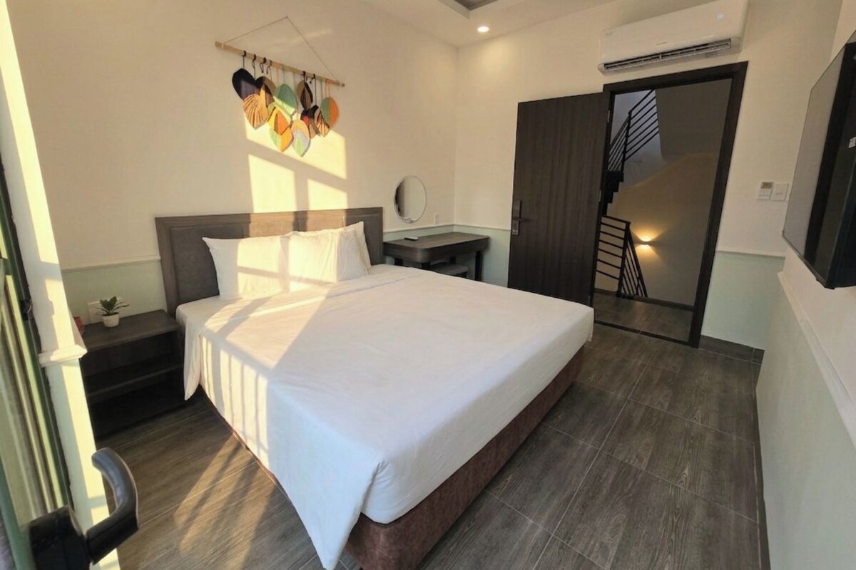 A hotel room with a large bed, a bedside table, a mirror, and a staircase leading to an upper level.