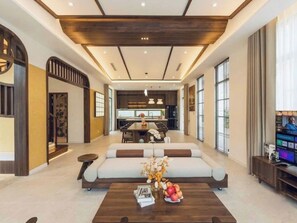 A modern living room with a sofa, coffee table, and a television. - Ocha Villa (Phu Quoc)
