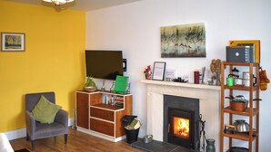Ein Wohnzimmer mit Kamin, Bücherregal, Sessel und einem Gemälde an der Wand.
