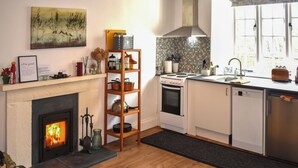 Eine moderne Küche mit Kamin, Holzregalen, einem Herd und einem Fenster mit Ausblick.